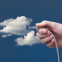 Eine Hand steckt ein LAN-Kabel in eine Wolke im Himmel